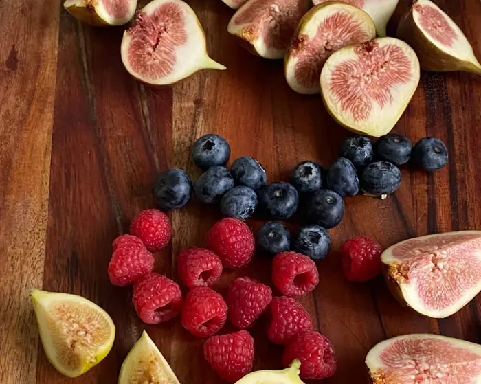 Halved figs with raspberries and blueberries on a board