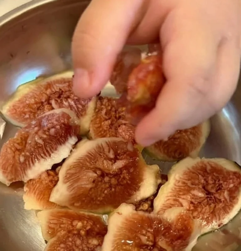 A little hand reaching for fig slices in a bowl