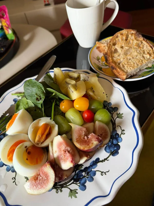Breakfast plate with fresh figs, boiled eggs, spinach and fruit